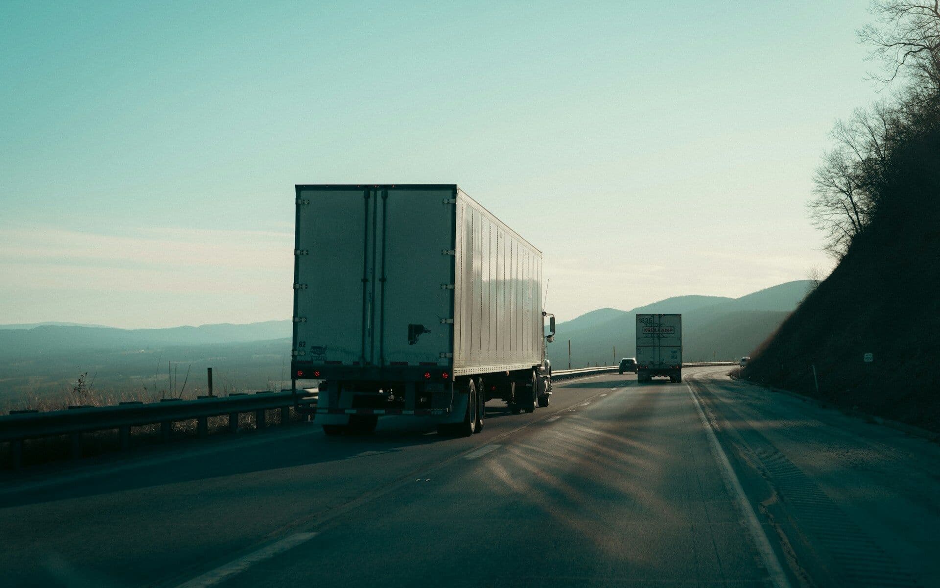 Semi-trailer trucks driving along a highway at dawn